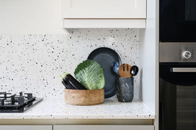 SIMPLE • STYLING The deep purple, greys and natural wood tones sit beautifully against the bright white terrazzo in our latest project. Along with the brushed brass pull detail, they also pick up on the contrast chips within the worktop 

#weluxit #kitchendesign #interiordesignsurrey #terrazzo #kitchenstyling #aubergine @academykitchens @melanietomlinsondesign